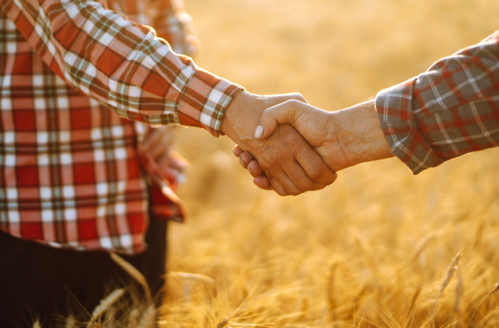 duas pessoas apertando as mãos após fechar acordo sobre commodities agrícolas